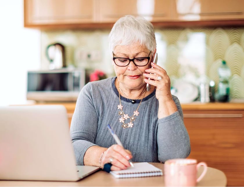 Older woman in front of a laptop speaking on the phone