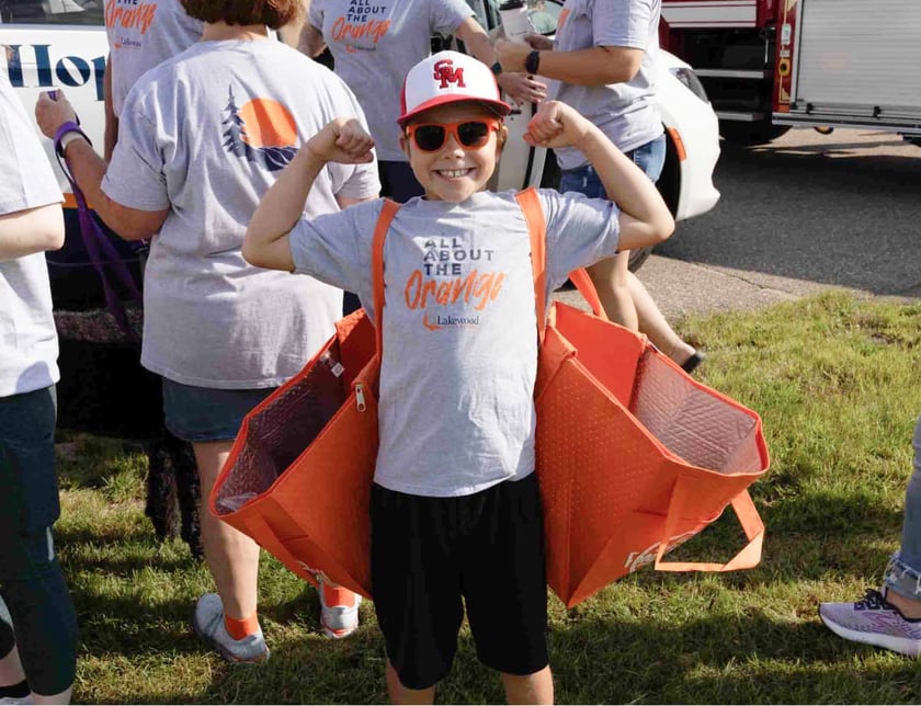 boy-flexes-muscles-wearing-lakewood-all-about-the-orange-shirt-at-lakewood-community-event