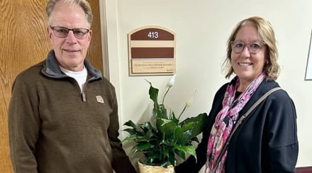 couple-smiles-beside-named-donor-room-plaque-with-peace-lily-plant