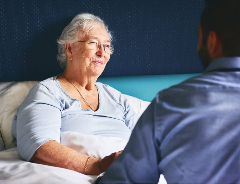 doctor-consults-with-elderly-woman-patient-in-hospital-bed