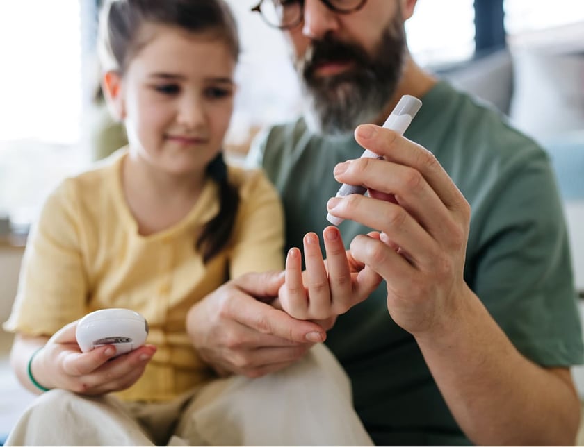 father_assisting_daughter_with_blood_sugar_test