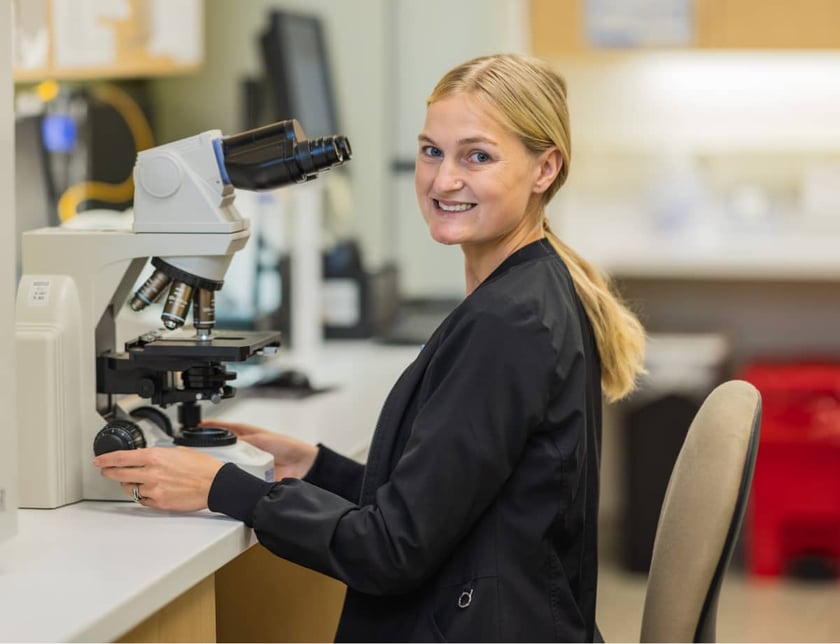 female-lab-technician-smiling-microscope-medical-laboratory
