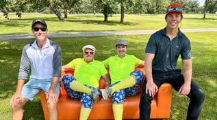 golfers-in-colorful-fancy-pants-pose-on-orange-couch-at-charity-golf-tournament