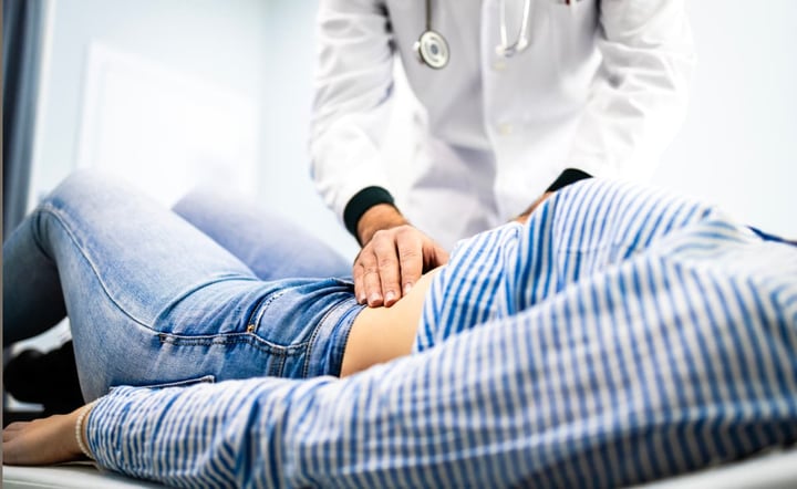 Doctor gastroenterologist palpates patient stomach. 