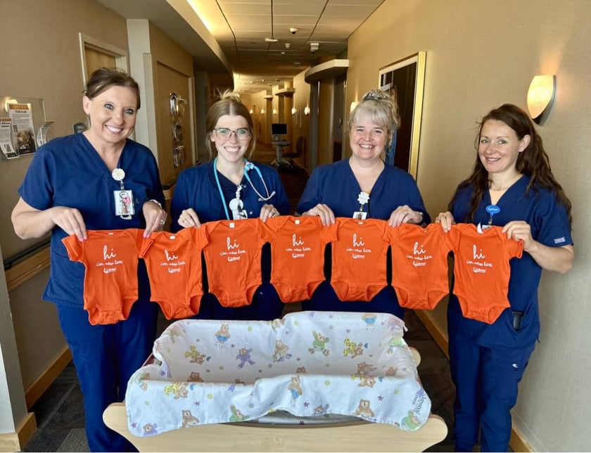 lakewood-health-system-maternity-nurses-holding-orange-baby-onesies-in-hospital-hallway
