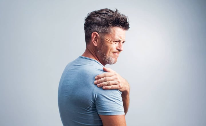 man-grimacing-while-holding-painful-shoulder