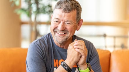 middle-aged-man-smiling-while-sitting-on-orange-couch