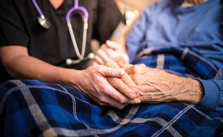 nurse-holds-elderly-patients-hand-during-hospice-care