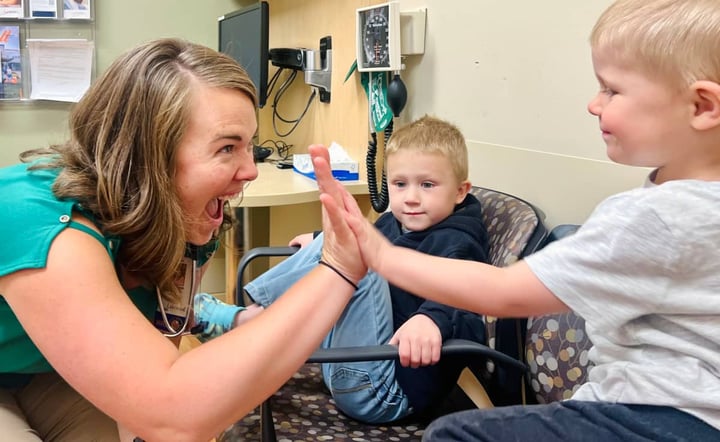 pediatric-nurse-high-fives-young-boy-during-clinic-visit