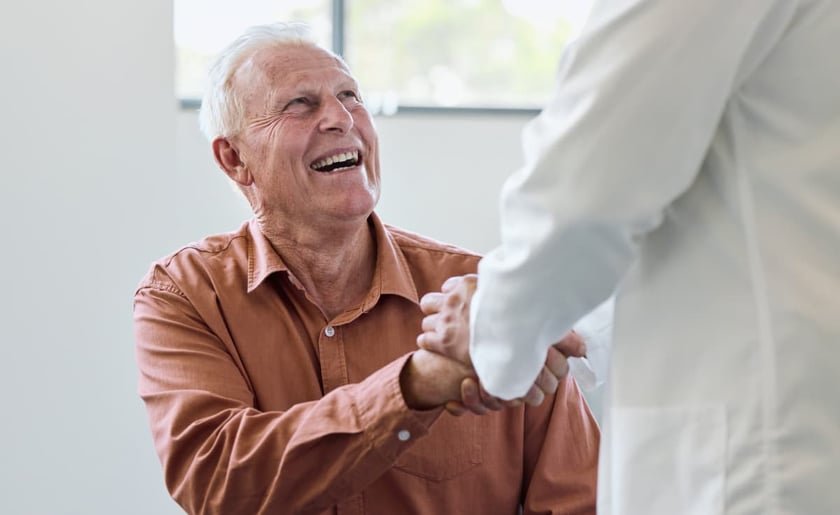 smiling_senior_male_holding_hand_of_doctor