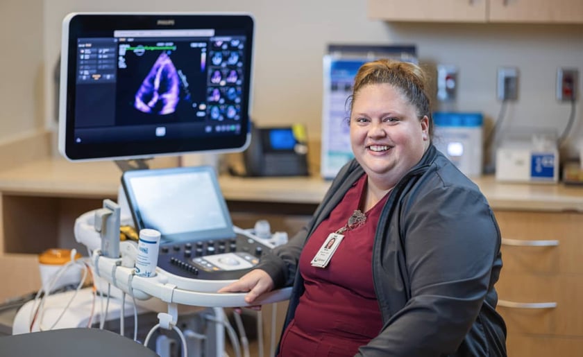 sonographer-smiles-beside-echocardiogram-ultrasound-machine