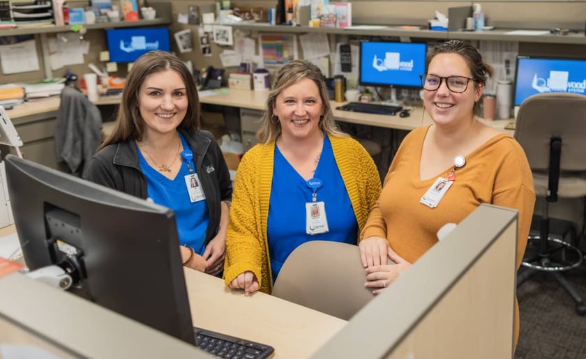 three-female-hospital-staff-smiling-at-nurses-station