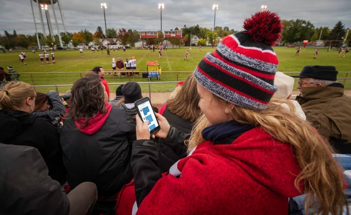 woman-at-football-game-using-click-care-on-phone-outdoors