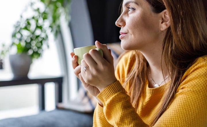 woman-holding-coffee-cup-gazing-off-in-the-distance