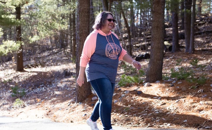 woman-smiling-while-walking-on-wooded-trail-outdoors