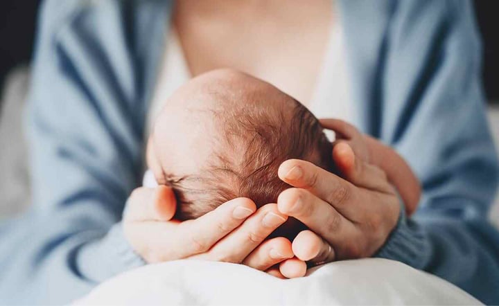 Mother holding newborns head